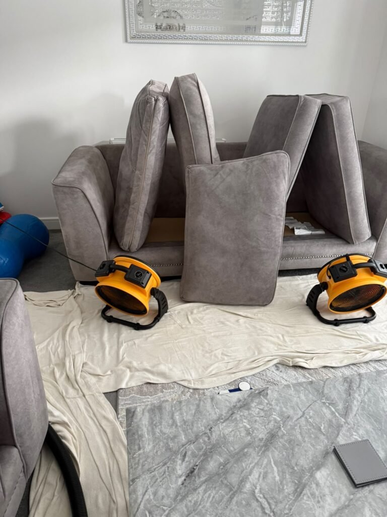 Grey sofa drying with air movers after cleaning